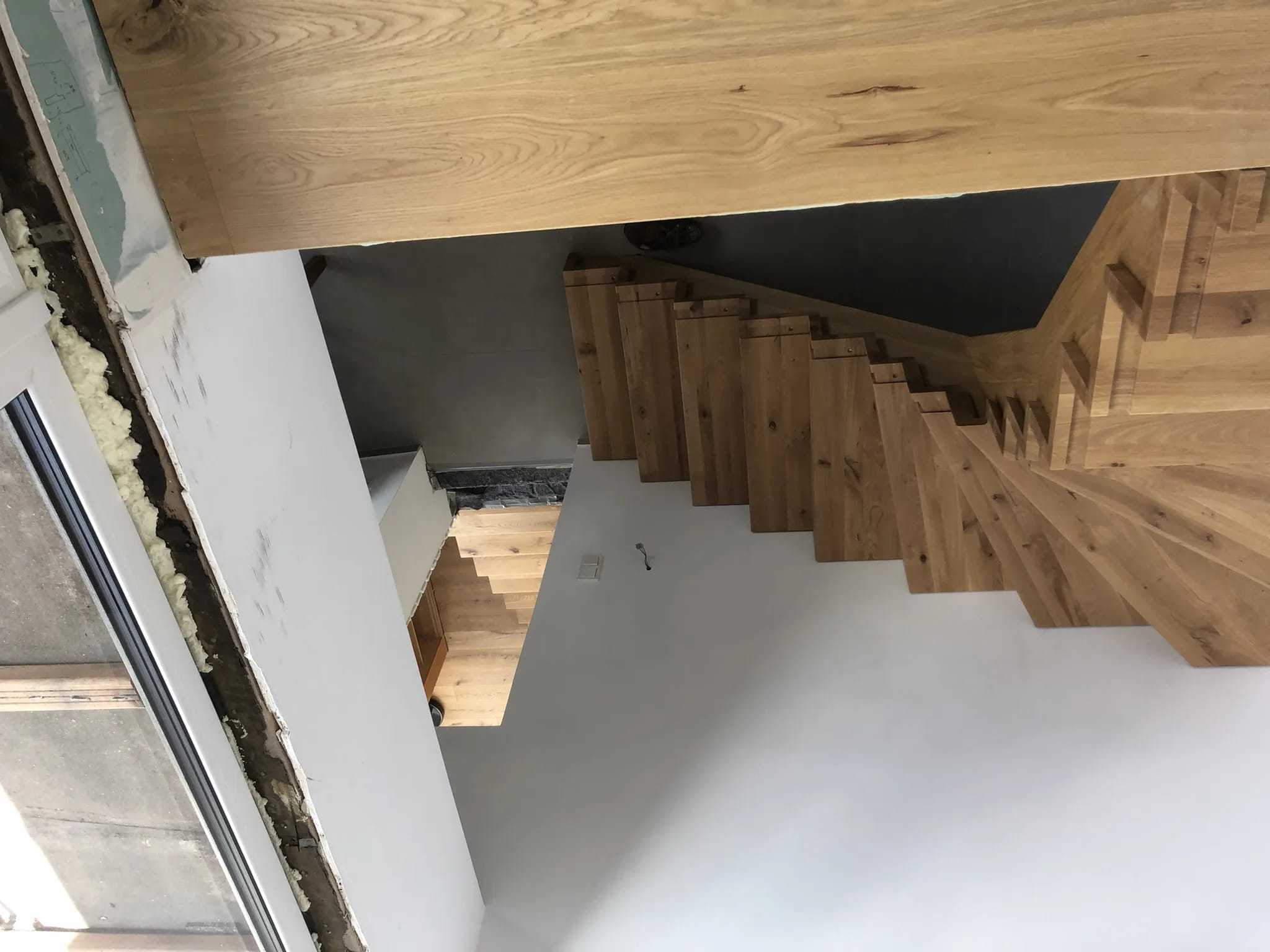 Folded staircase on stringer beams in oak with white balustrade and oak risers — manufactured in our Witten workshop